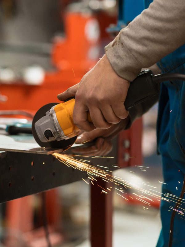 Technician worker cutting metal with many sharp sparks. Using equipments to cat iron